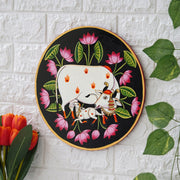 This beautiful pichwai painting features the Hindu deity Krishna cradling his beloved calf, surrounded by a vibrant array of flowers.